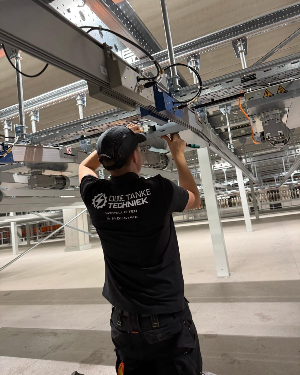 Monteur bevestigt de aandrijving van een transportbaan aan de staalconstructie