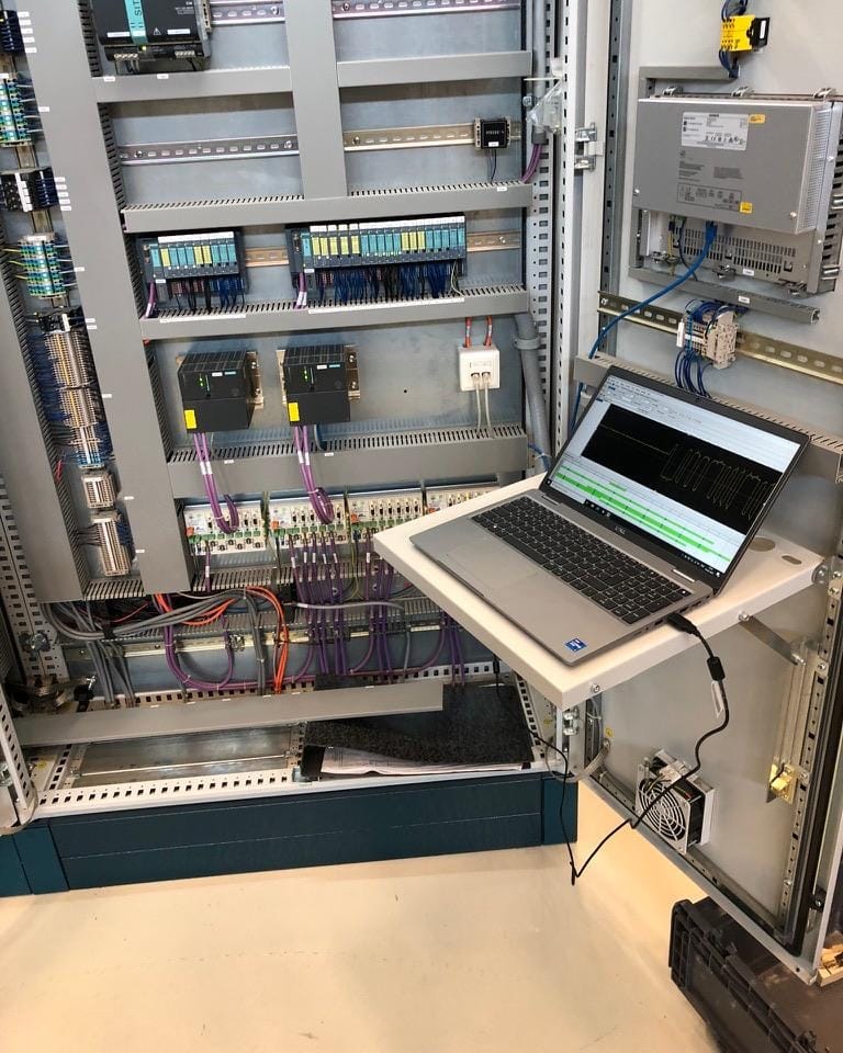 Geopende besturingskast met PLC en aangesloten diagnoselaptop