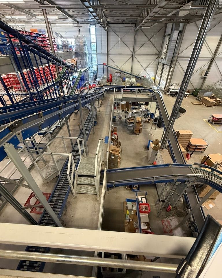 Heftruckchauffeur en monteur op een hoogwerker tijdens de opbouw van een magazijninstallatie