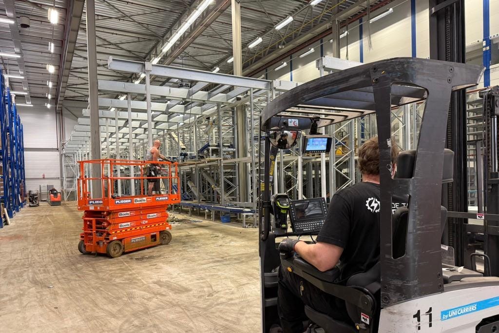 Overzicht vanaf de mezzanine op blauwe transportbanen die door de hal lopen